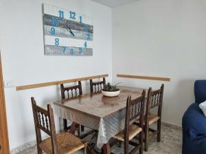 a dining room with a table with chairs and a clock at Torre Hirta 1 in Peniscola