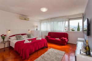 1 dormitorio con cama roja y silla roja en Beach Split Apartments, en Split