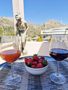 zwei Gläser Wein und eine Schale Erdbeeren auf dem Tisch in der Unterkunft Kalogria Beach Apartments in Kalogria