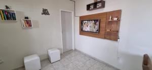 Habitación con 2 sillas blancas y TV en la pared. en Espaço do acalanto en Natal
