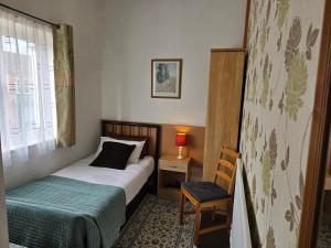 a bedroom with a bed and a chair and a window at Fairhaven Guest Accommodation in Nottingham