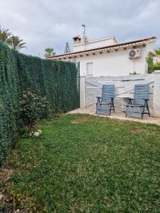 two blue chairs and a table in a backyard at La casita de invitados in Denia +7 photos