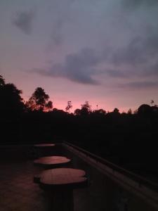 a group of picnic tables on a balcony at sunset at Lanka Peter's House Tourist Guest House & Restaurant in Peradeniya