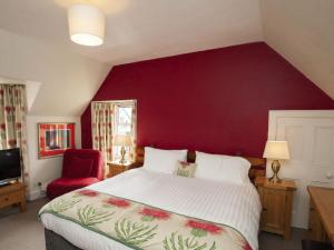 sypialnia z dużym łóżkiem i czerwoną ścianą w obiekcie Holiday Home Oakdale House by Interhome w mieście Drumnadrochit