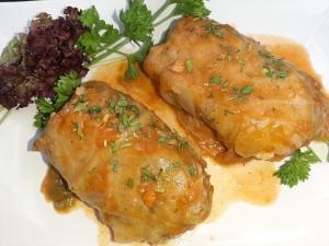 two pieces of meat with sauce and vegetables on a white plate at Wodnik in Pisz