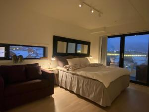 een slaapkamer met een bed, een bank en een raam bij The Heart of Tromsø city Apartment in Tromsø