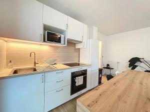 cocina con armarios blancos, fregadero y encimera en Le Martray - Spacieux - 4 chambres, en Rennes 3 fotos más