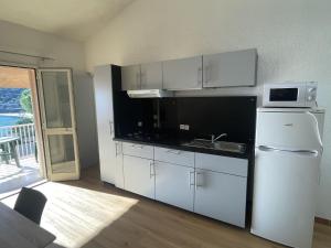 a kitchen with white cabinets and a sink and a microwave at Apartment Le Télémaque 2 pièces Mezzanine by Interhome in Conca
