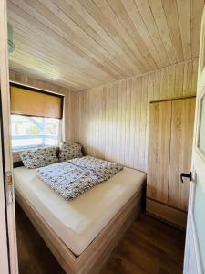 a bed in a small room with wooden walls at Domki Asia - Muszelki 68 in Nowęcin