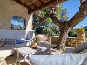 een patio met een tafel en stoelen en een boom bij Holiday Home La Bastide de Magdeleine by Interhome in Laouque