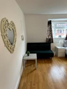 Cozy Room in whitechapel! Central London في لندن: غرفة معيشة مع أريكة خضراء ومرآة