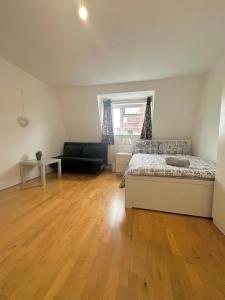 a bedroom with a bed and a couch and wooden floors at Cozy Room in whitechapel! Central London in London