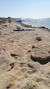 ein Strand mit einem blauen Sonnenschirm und Sand und Wasser in der Unterkunft Casa vacanze a 100mt dal mare in Torre Ovo