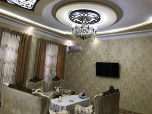 una sala da pranzo con tavolo e lampadario pendente di Шербудин a Bukhara