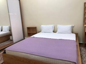 um quarto com uma cama grande e um cobertor roxo em Шербудин em Bukhara