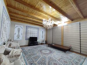 un soggiorno con divano e lampadario pendente di Шербудин a Bukhara