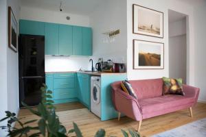 a kitchen with blue cabinets and a pink couch at Studio Apartment in Warszawa Wola in Warsaw