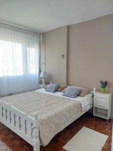 een wit bed in een slaapkamer met een raam bij Apartman Maja in Banja Luka