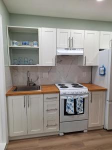 a kitchen with white cabinets and a stove and a sink at Casa Del Sol in Lauderhill