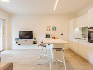 a white kitchen with a table and a tv at Apartment Am See by Interhome in Riva del Garda +33 photos