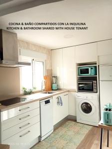 kuchnia z białymi szafkami, pralką i suszarką w obiekcie Luminosa habitación w Sewilli