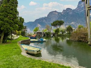 a group of boats on a river with mountains in the background at Apartment Am See by Interhome in Riva del Garda