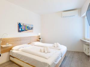 two beds in a room with white walls at Apartment Am See by Interhome in Riva del Garda