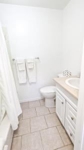a white bathroom with a toilet and a sink at Oasis by the Bay Vacation Suites in Wasaga Beach