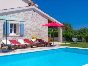 - un groupe de chaises longues et de parasols à côté de la piscine dans l'établissement Villa Azura by Interhome, à Marčana