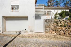a white house with a garage and a stone wall at Villa da floresta in Arcos