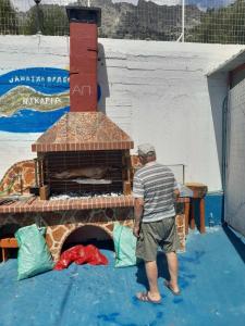 a man standing in front of a brick oven at Ikaria Studios in Manganítis