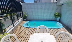 a pool on a deck with two chairs and a table at Tempo de Aconchego Hospedagens Tambaú 100m da Praia in João Pessoa