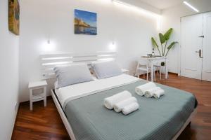 una camera da letto bianca con un letto e asciugamani di Due metri sopra al mare a Otranto