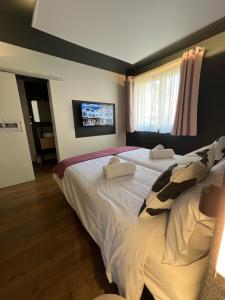 a bedroom with two beds and a tv on the wall at Hôtel Restaurant & Spa du Tremplin in Bussang