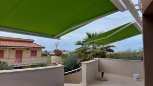 a green canopy on a balcony with a house at VELA BIANCA in Punta Braccetto
