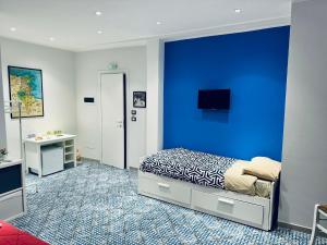 a bedroom with a blue wall with a bed and a desk at Corleone Home in Corleone