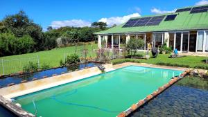 uma piscina com uma casa com telhado solar em ReRooted Permaculture Farmstay em Howick