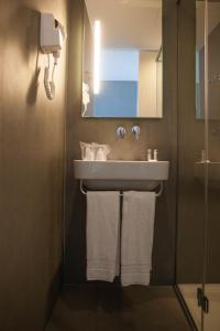 uma casa de banho com lavatório e toalhas penduradas em Hotel Costa Verde na Póvoa do Varzim