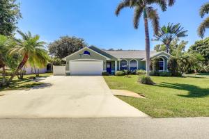 a house with palm trees and a driveway at Jensen Beach Home with Heated Pool! in Jensen Beach