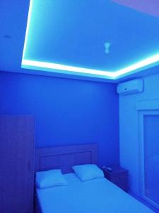 a blue room with a bed with a light on the ceiling at Norespaço - Le cap sud in Tarrafal