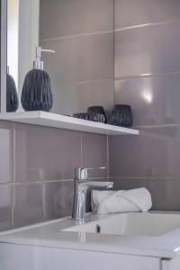 baño con lavabo, espejo y algunos jarrones en Trioasis - 3 chambres, en Reims