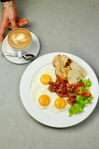 a plate of eggs and bacon and a cup of coffee at Hotel Apartments Adresa in Chişinău