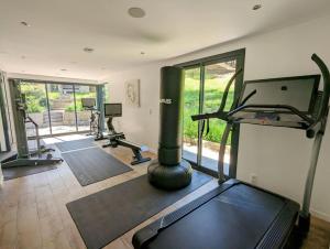 a fitness room with a gym with tread machines at Villa de 7 chambres avec vue sur la ville piscine interieure et jardin clos a Parmain a 2 km de la plage in Parmain