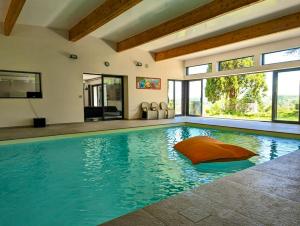 een zwembad met een oranje kussen in een huis bij Villa de 7 chambres avec vue sur la ville piscine interieure et jardin clos a Parmain a 2 km de la plage in Parmain