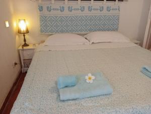 a bed with a towel and a flower on it at Casa Helichrysum in Forte Village