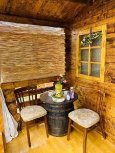 a wooden cabin with a table and two chairs at Camping Mala Clisura Dunării in Eşelniţa