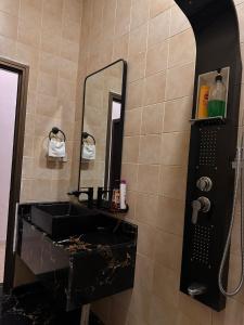 La salle de bains est pourvue d'un lavabo noir et d'un miroir. dans l'établissement شقق ارجان نجد المفروشه, à Al Nairyah