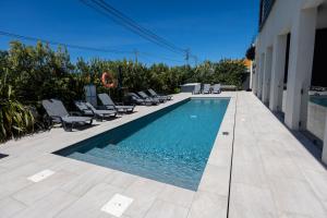 a swimming pool with lounge chairs next to a building at Ribamar Bluevillas T1 by ACasaDasCasas - Apartment 3 in Ericeira