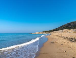 una spiaggia sabbiosa con l'oceano e le montagne sullo sfondo di Kalogria Beach Apartments a Kalogria