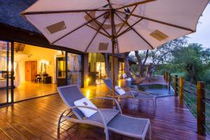 a deck with chairs and an umbrella and a pool at Naledi Lodges in Balule Game Reserve